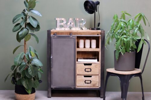 Meuble d'entrée en bois et en métal mis en situation, entouré de plantes, lumières et autres décorations