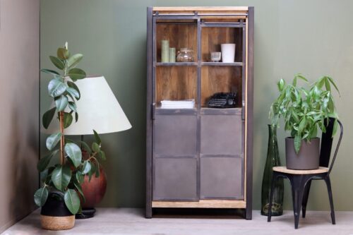 Vitrine en bois et en métal mise en situation, entourée de plantes et autres décorations